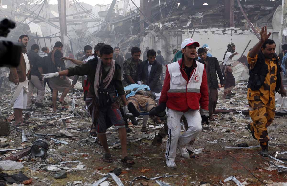 Yemeni medics and rescue workers carry a body on a stretcher amid the destruction of a funeral hall at the site of reported airstrikes by Saudi-led coalition air-planes in the capital Sanaa on October 8, 2016.